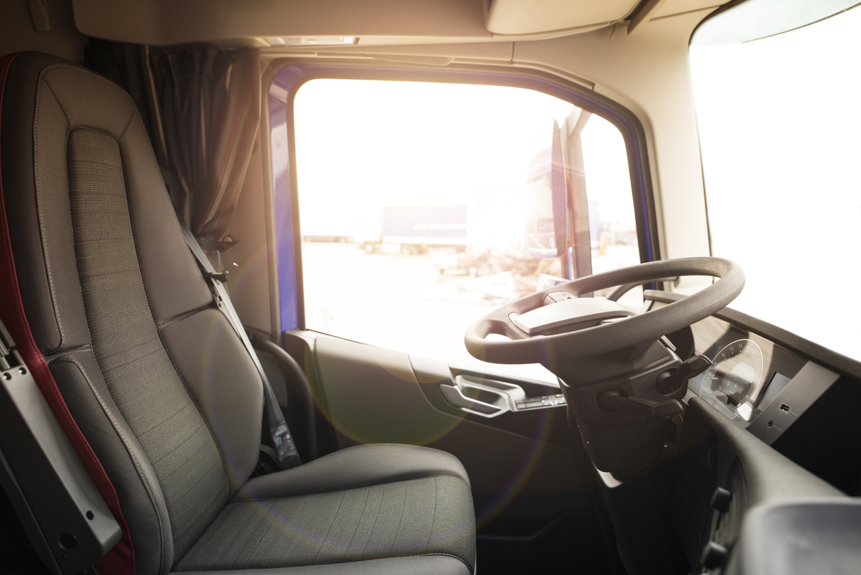 Truck vehicle interior with driver seat and steering wheel.