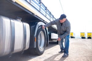 A truck driver inspects the tire of his truck
