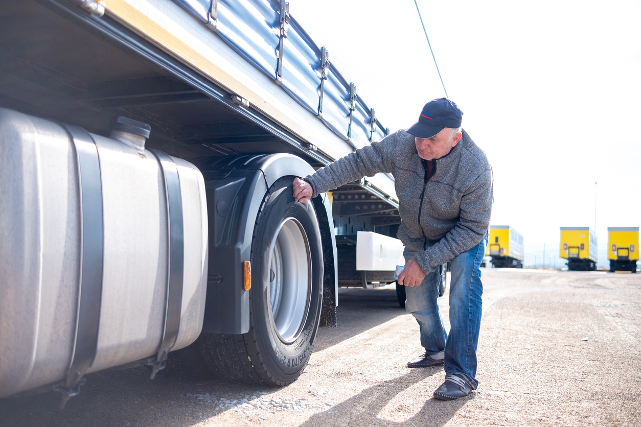 A truck driver inspects the tire of his truck