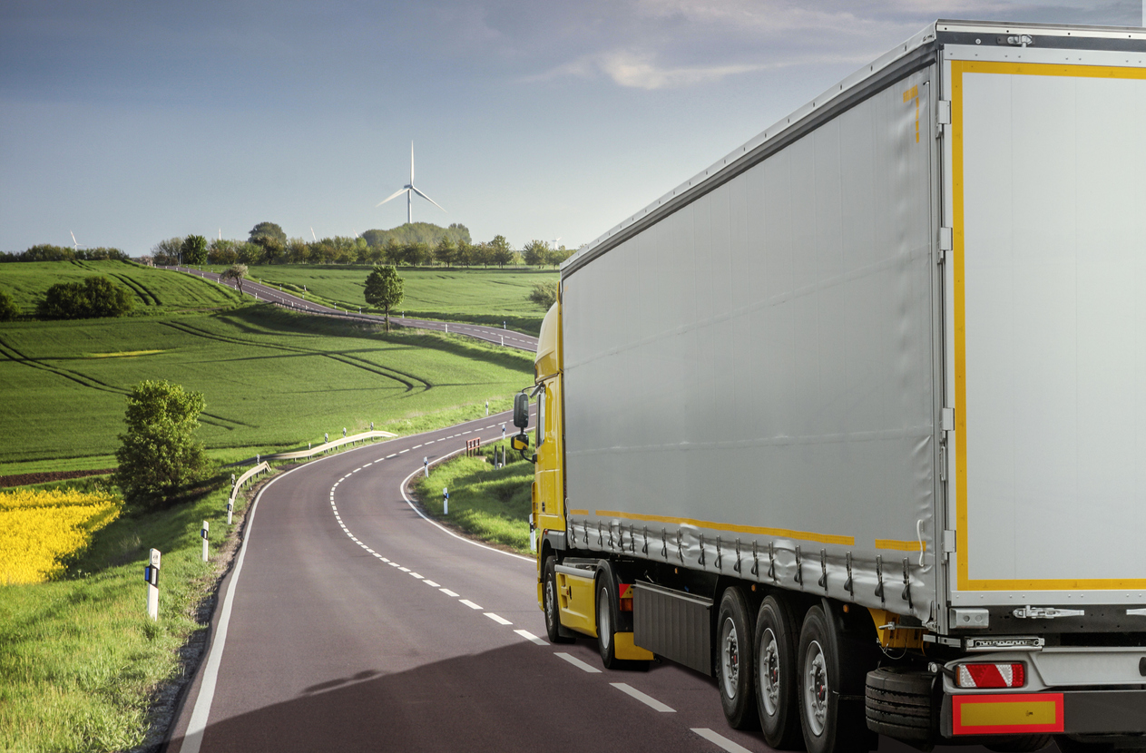 truck driving down road with green landscape