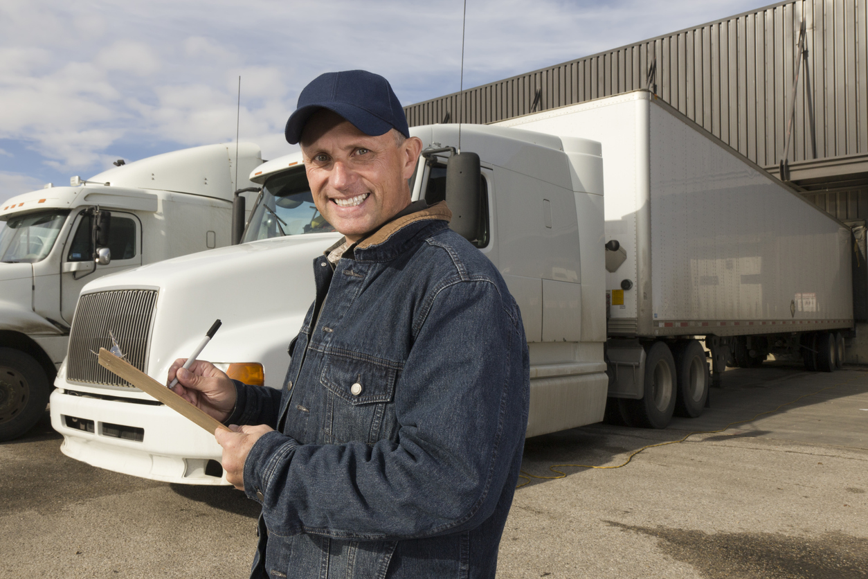 A royalty free image from the trucking industry of a truck driver in front of a semi truck.