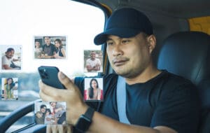 semi-truck driver happy smiling and looking smartphone in his hand show images virtual people. Bearded Asian man Video call to chat and greet friends and family with modern communication technology.