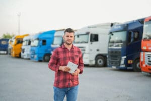 man holding tablet in front of trucks in truck park