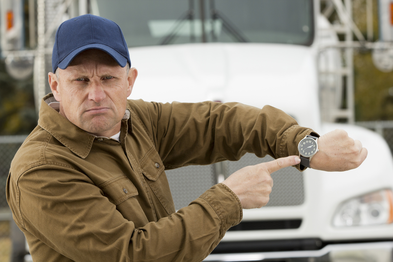 angry and frustrated truck driver pointing at his watch.