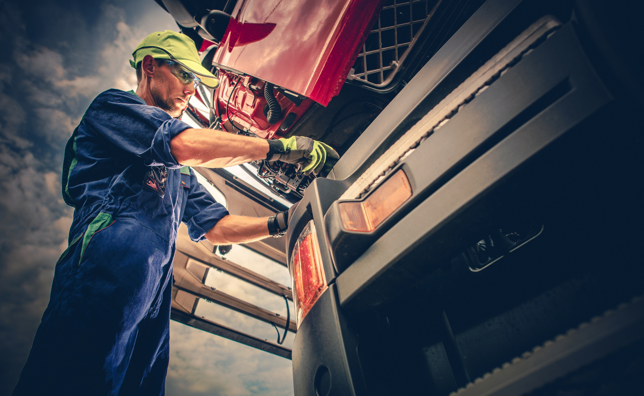 Semi Truck Maintenance. Caucasian Truck Service Worker in His 30s Performing Scheduled Recall Maintenance.