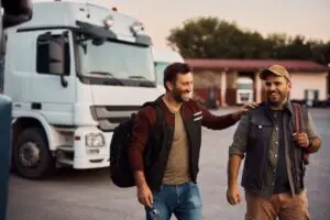 Two cheerful truck drivers having fun in a parking lot before their weekday training, as opposed to feeling frustrated and lost at weekend CDL schools