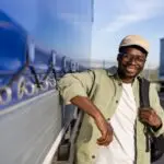 A man with a good truck driver work life balance smiles while leaning against his truck